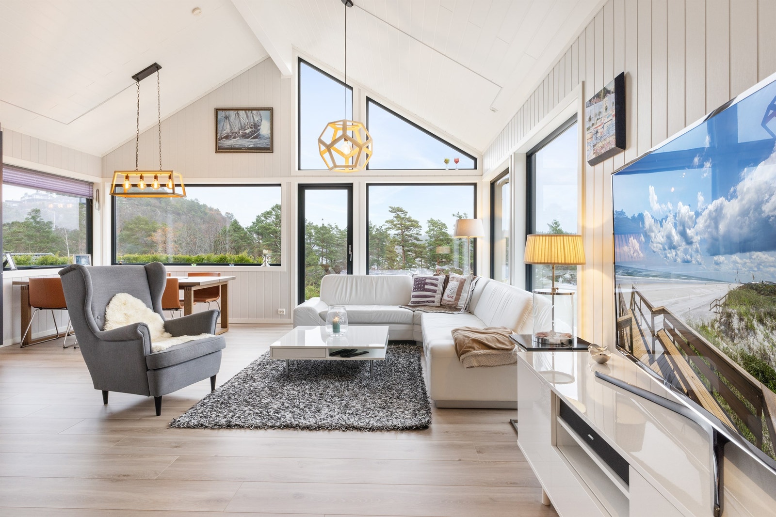 Stor stue med åpen løsning til kjøkken, samt store vindusflater mot fjorden Galleribilde