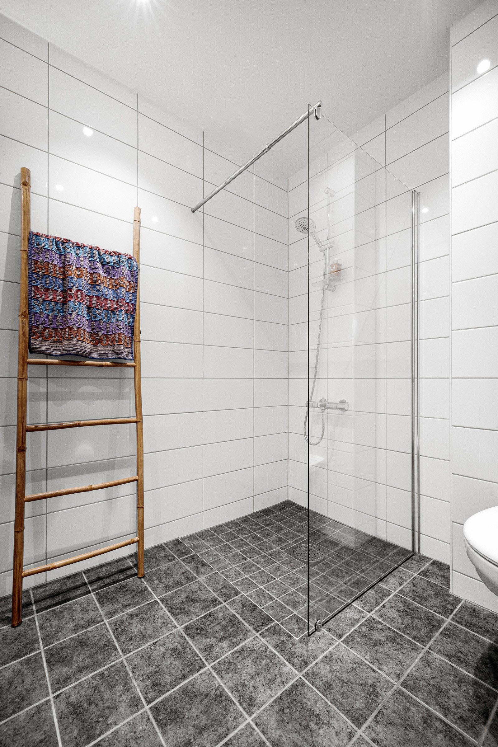 Rommet har innredning med nedfelt servant, veggmontert toalett og dusjvegger/hjørne. Galleribilde