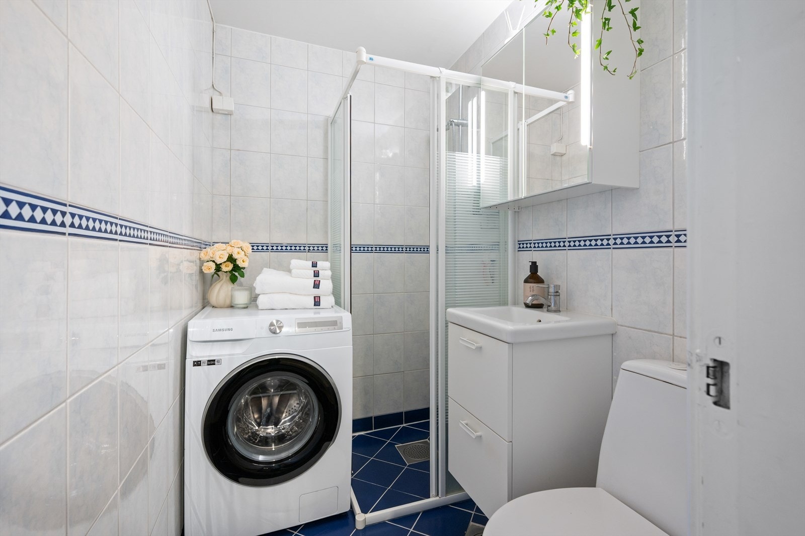 Flislagt bad med elektrisk gulvvarme. Badet er innredet med dusjhjørne med skyvedører, klosett og servant med skapplass. Galleribilde