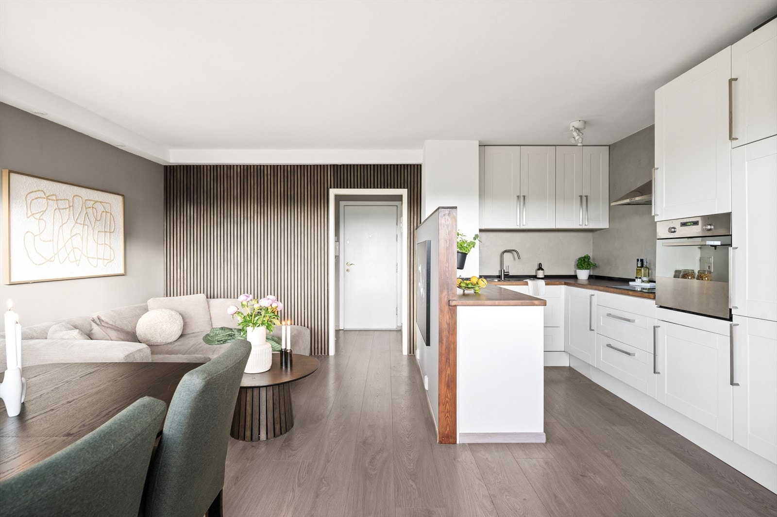 Praktisk og stilren kjøkkeninnredning med integrert induksjonstopp, stekeovn, oppvaskmaskin og kjøl/frys. Galleribilde