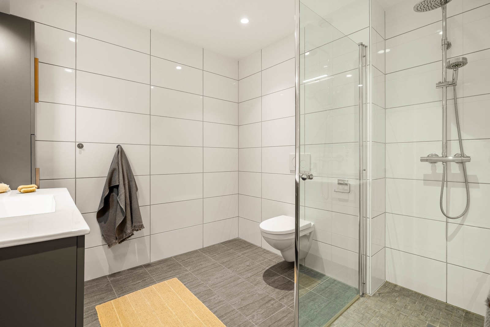 Badet inneholder baderomsinnredning med ekstra skap for oppbevaring, dusjvegger og toalett. Galleribilde