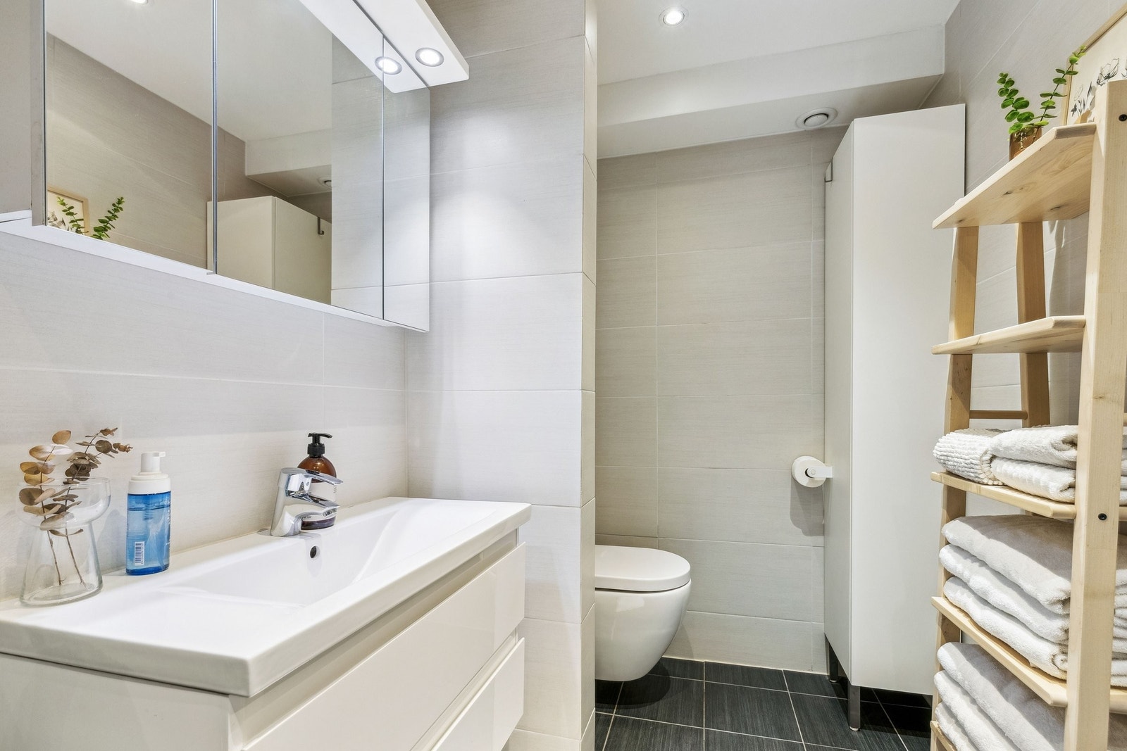 Badet ble pusset opp i 2014 og fremstår moderne med lyse fliser, vegghengt toalett og stilren innredning med god oppbevaringsplass Galleribilde