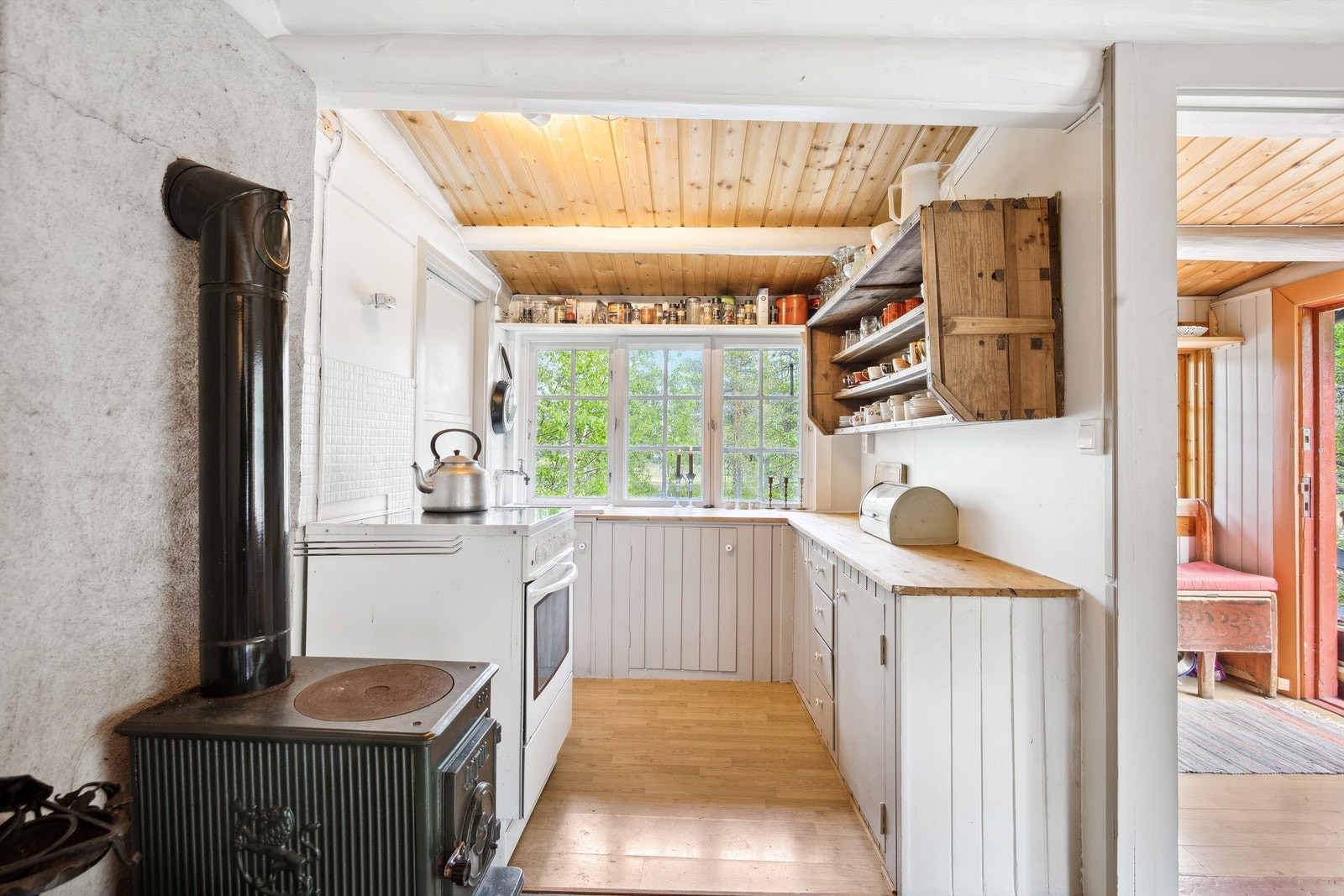 Kjøkkenet har plassbygget innredning av trepanel, overskap på vegg og heltre benkeplate med utslagsvask med vannkran Galleribilde