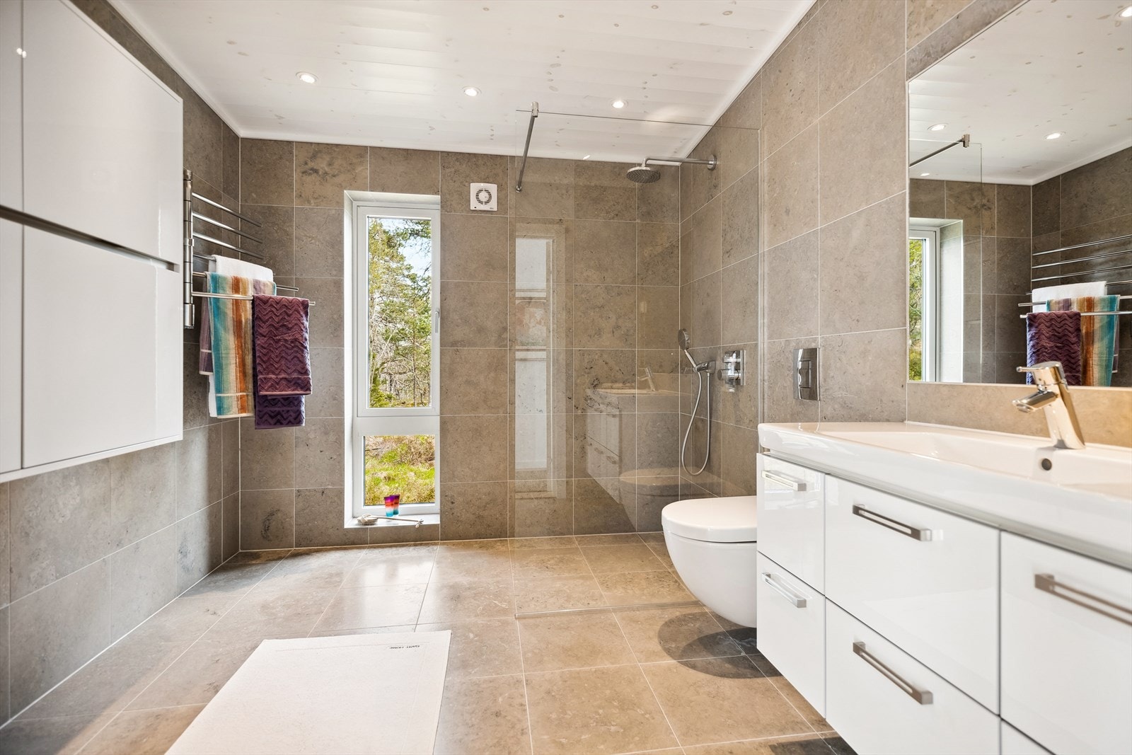 Baderommene, begge med toalett og dusj, har gulv og vegger i Atazul slipt naturstein fra Stenprosjekt. Galleribilde