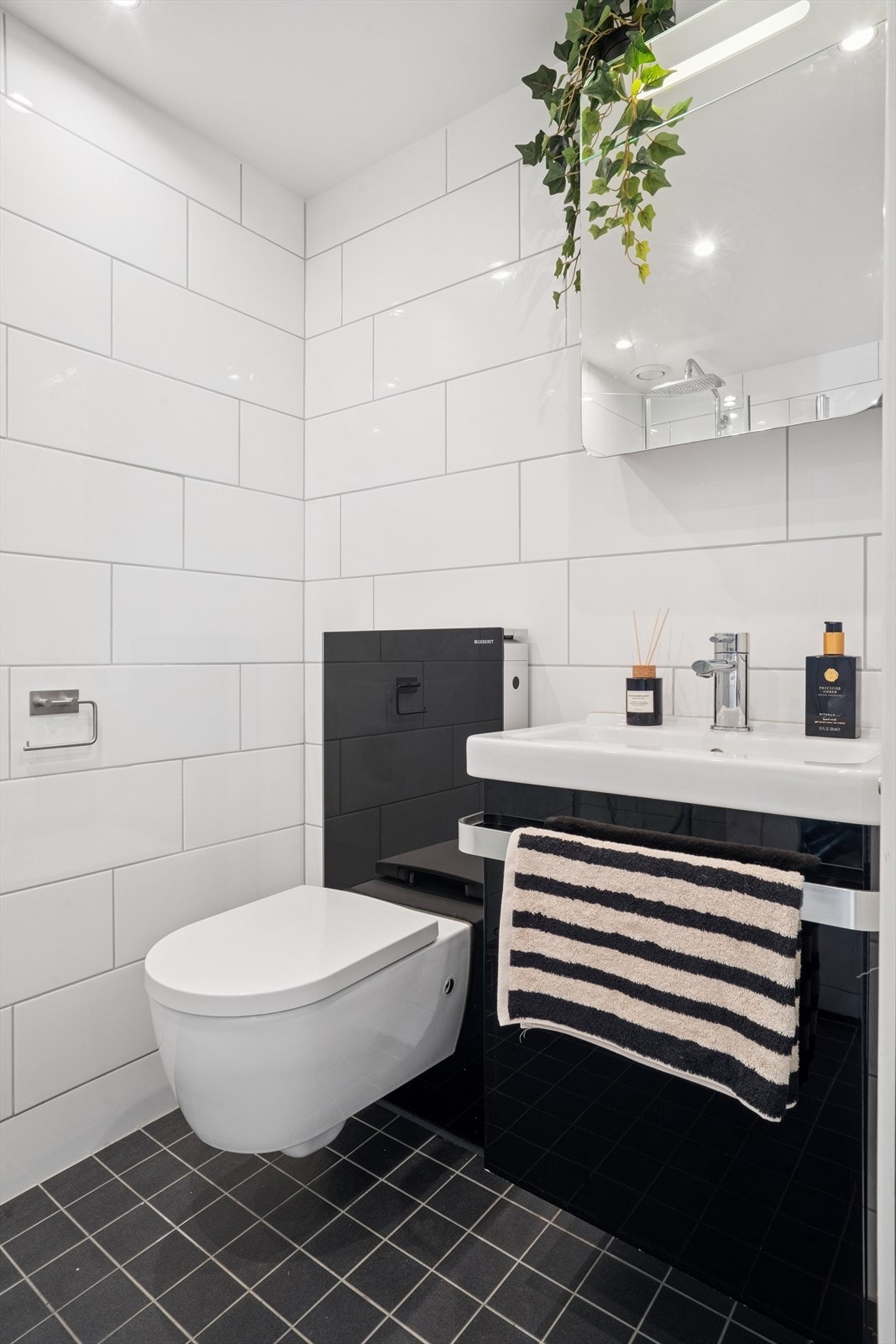 Badet er moderne utstyrt med vegghengt toalett og en sort servantinnredning. Galleribilde