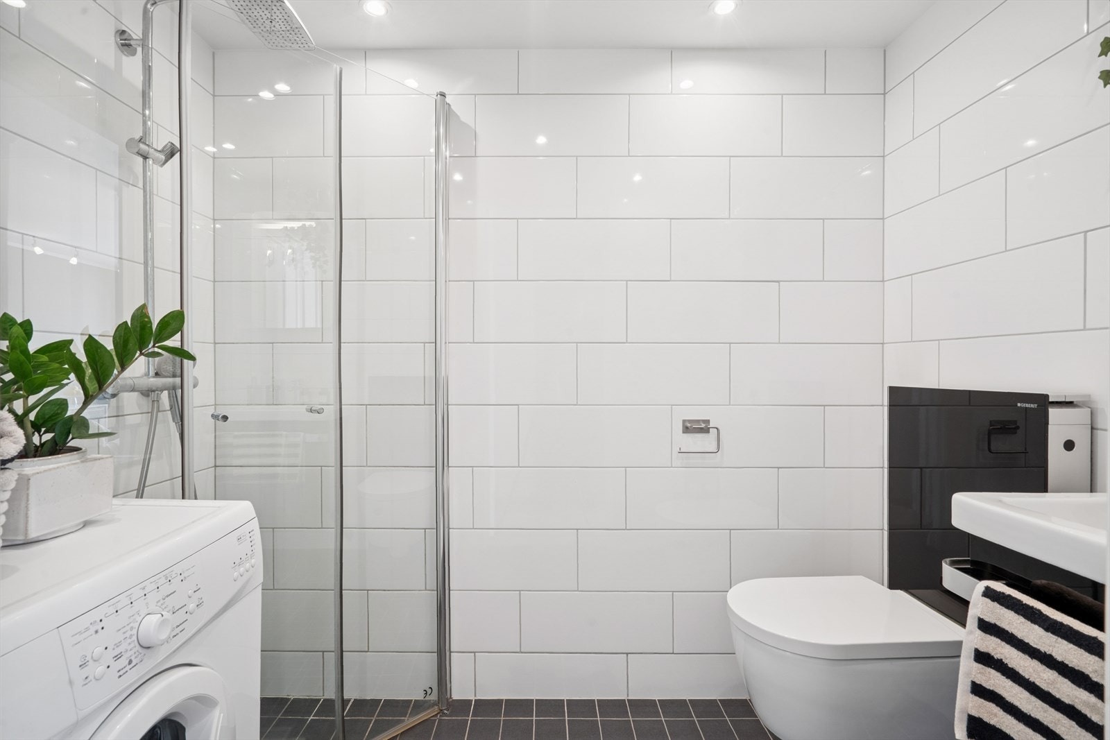 Badet har en flott utførelse med hvite fliser på veggene og mørke fliser med varme på gulvet. Galleribilde