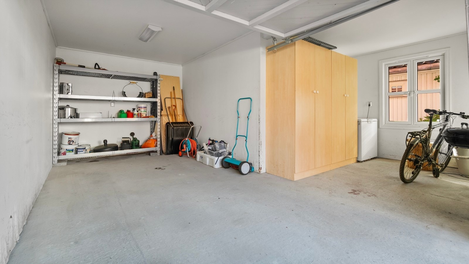 Innlemmet garasje i 1. etasje, med én biloppstillingsplass og tilliggende bodareal. Vippeport og dør for tilkomst. Galleribilde
