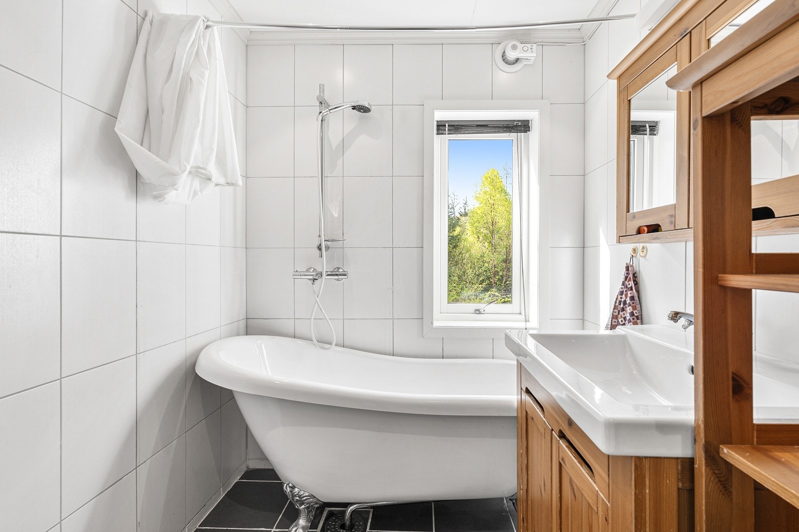 Baderommet er innredet med badekar med dusjløsning, vegghengt toalett, samt servant med innredning, speil og belysning. Galleribilde