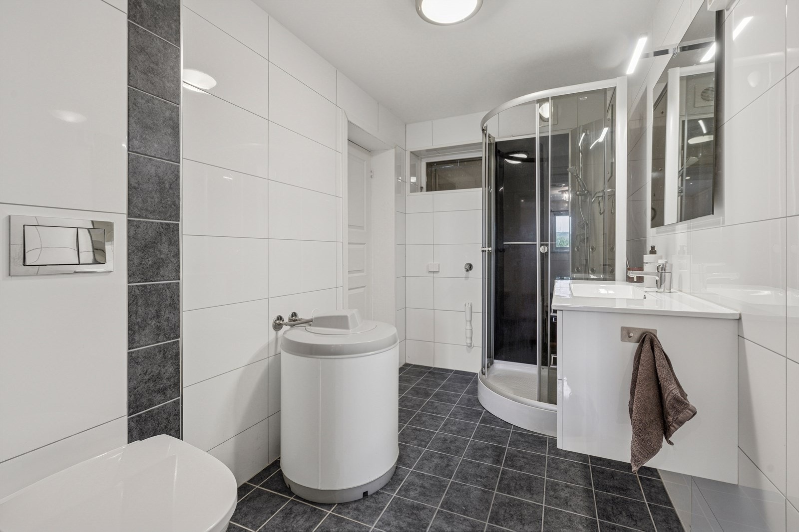 I hybel 2 er det et baderom fra 2016. Badet har en innredning med heldekkende servant, veggmontert toalett, dusjkabinett og opplegg for vaskemaskin. Galleribilde