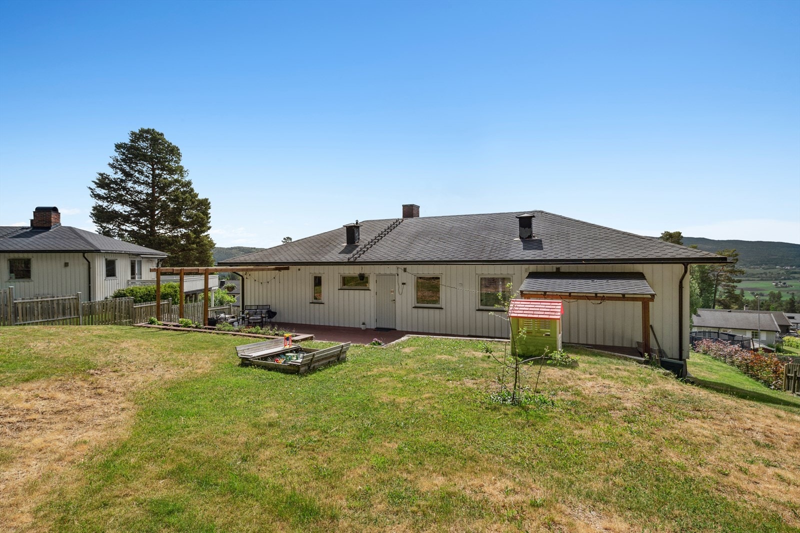 Eiendommen har en pent opparbeidet tomt med asfaltert innkjørsel og gressplen med beplantning. Galleribilde