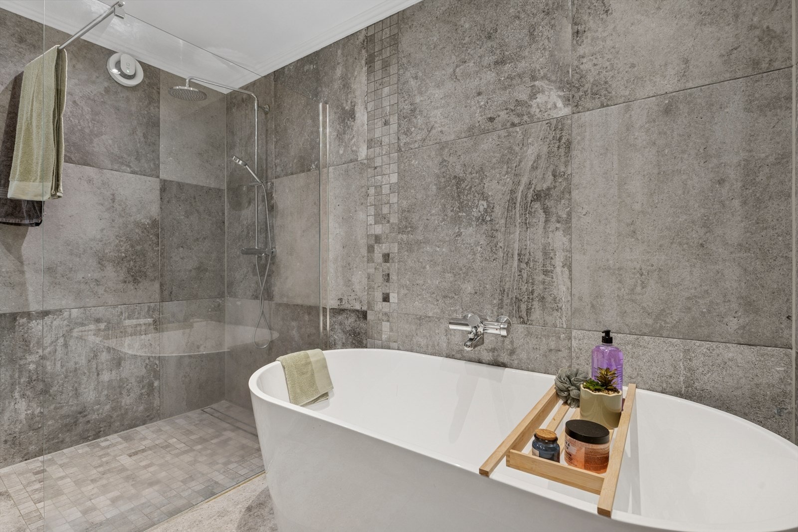 Badet har en innredning med 2 nedfelte servanter, veggmontert toalett, frittstående badekar og regnfallsdusj med glassvegg. Galleribilde