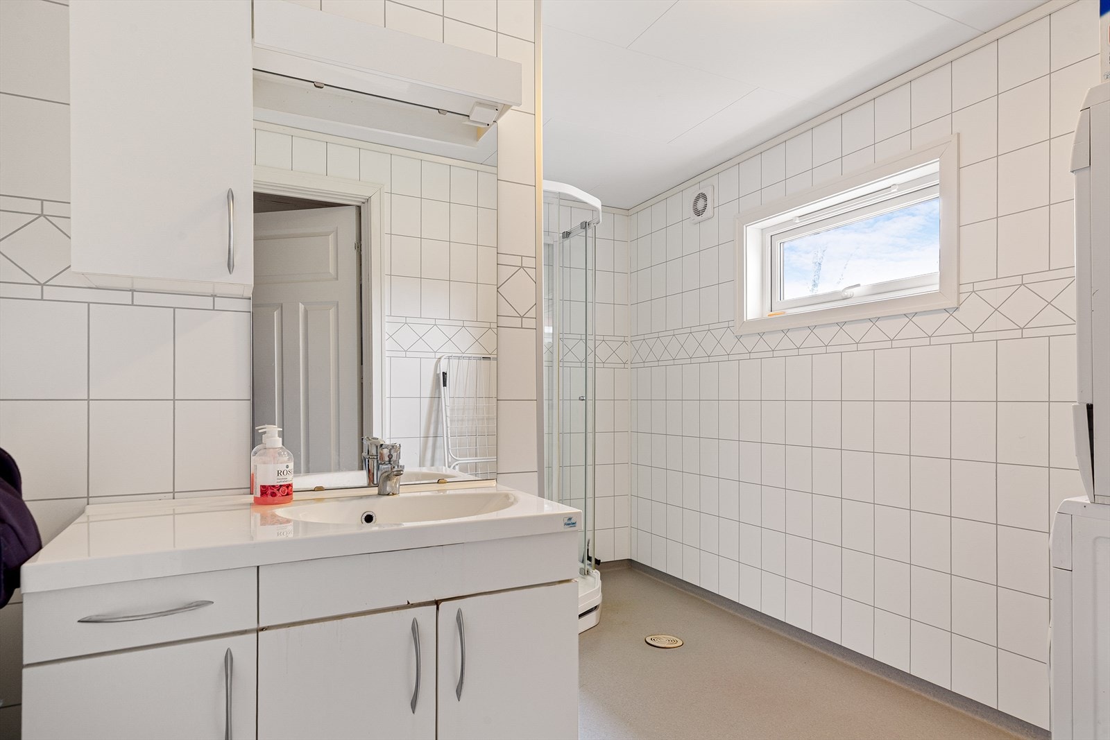 Pent bad på 7 m² med innredning i hvite, glatte fronter. Gulvvarme. Galleribilde