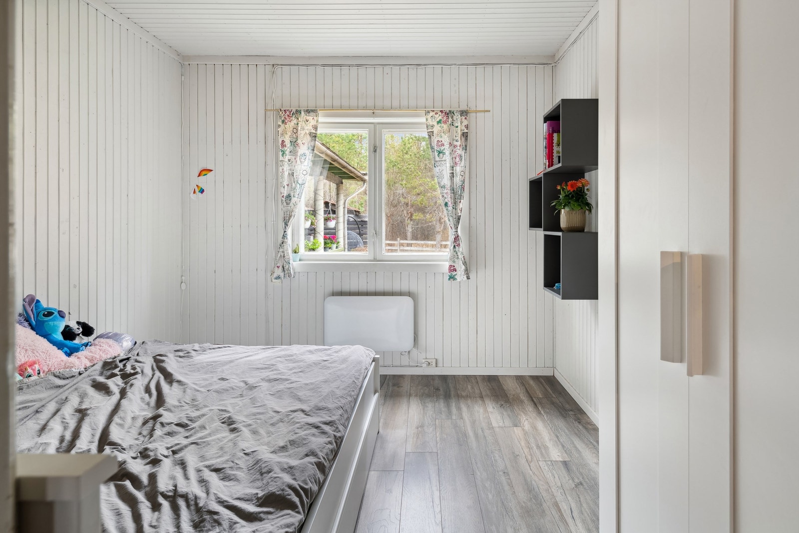 Det tredje soverommet har hvitmalt panel på veggene og i himling og mørk laminat på gulvet. Rommet har panelovn montert på vegg som varmekilde og ett dobbelt garderobeskap. Galleribilde