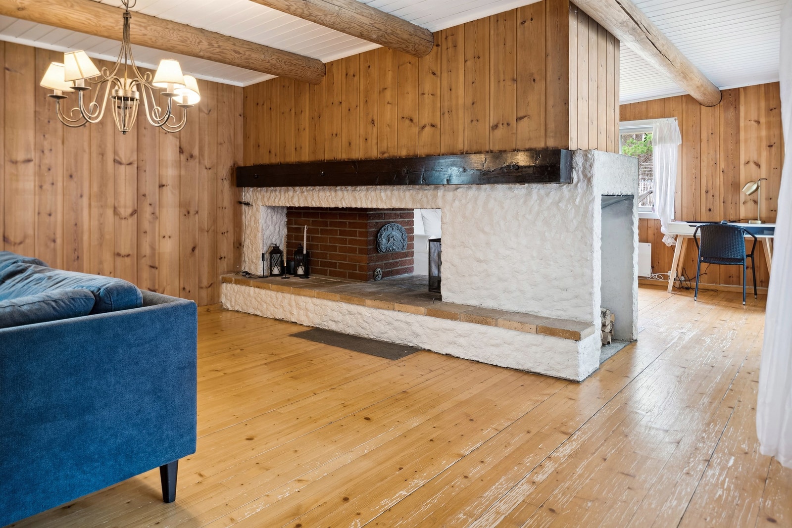 Stuen er romslig og delvis avdelt med en åpen plassbygd peisovn og tilknyttet vedovn midt i rommet. Galleribilde