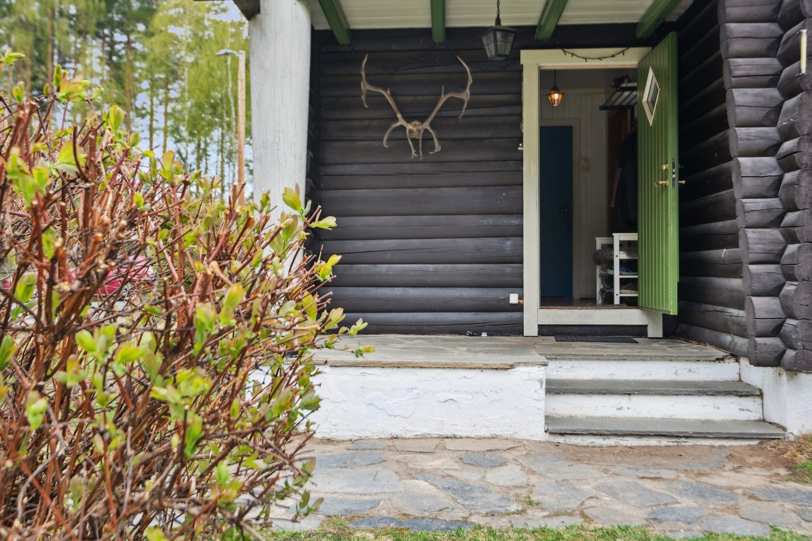 Her kommer man inn via et overbygget inngangsparti med murt steintrapp og liten murt platting med steinheller. Galleribilde