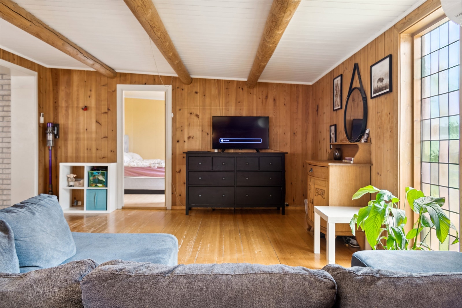 Panelovn montert på vegg. Flere vinduer på veggen ut mot terrassen slipper dagslyset flott inn i stuen. Galleribilde