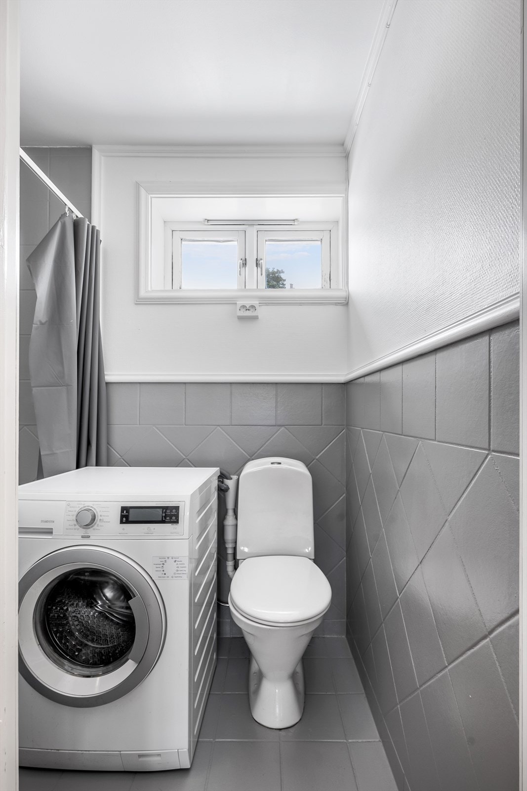 Badet har malte fliser og tapetserte overflater, gulvvarme og røropplegg for vaskemaskin. Galleribilde