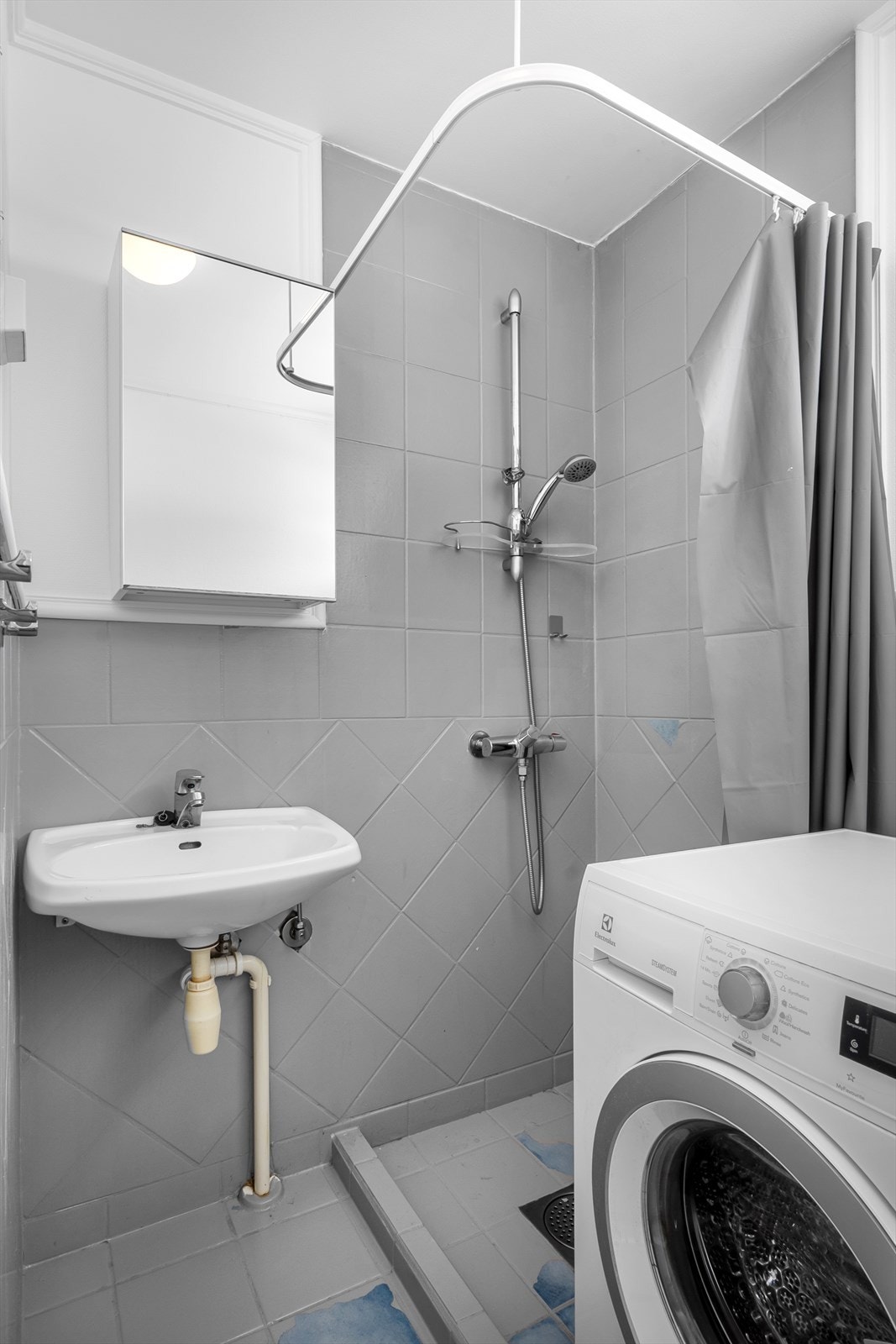 Videre er det dusjnisje med dusjforheng, enkel vegghengt servant og speilskap. Galleribilde