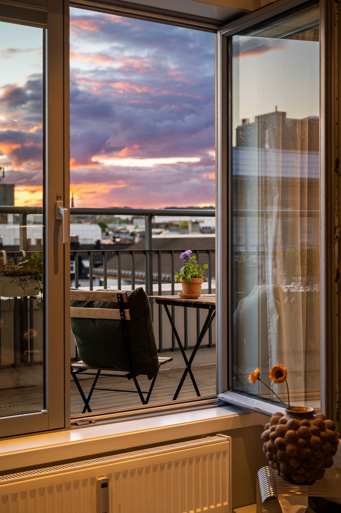 Utsikt mot balkong med bord og stoler, og solnedgang i bakgrunnen. Galleribilde