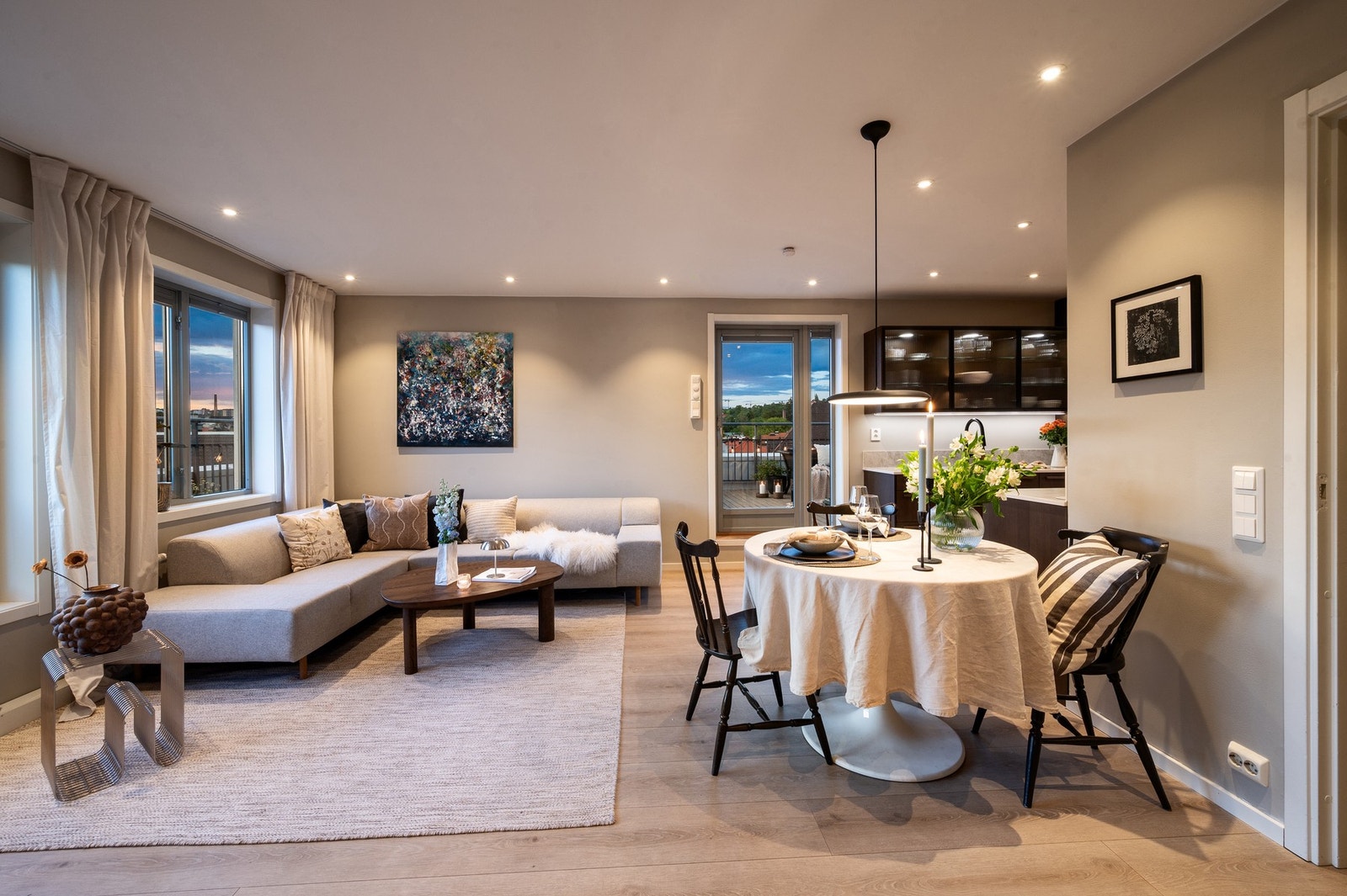 Lys stue med åpen løsning til kjøkken, spiseplass og utgang til balkong. Galleribilde