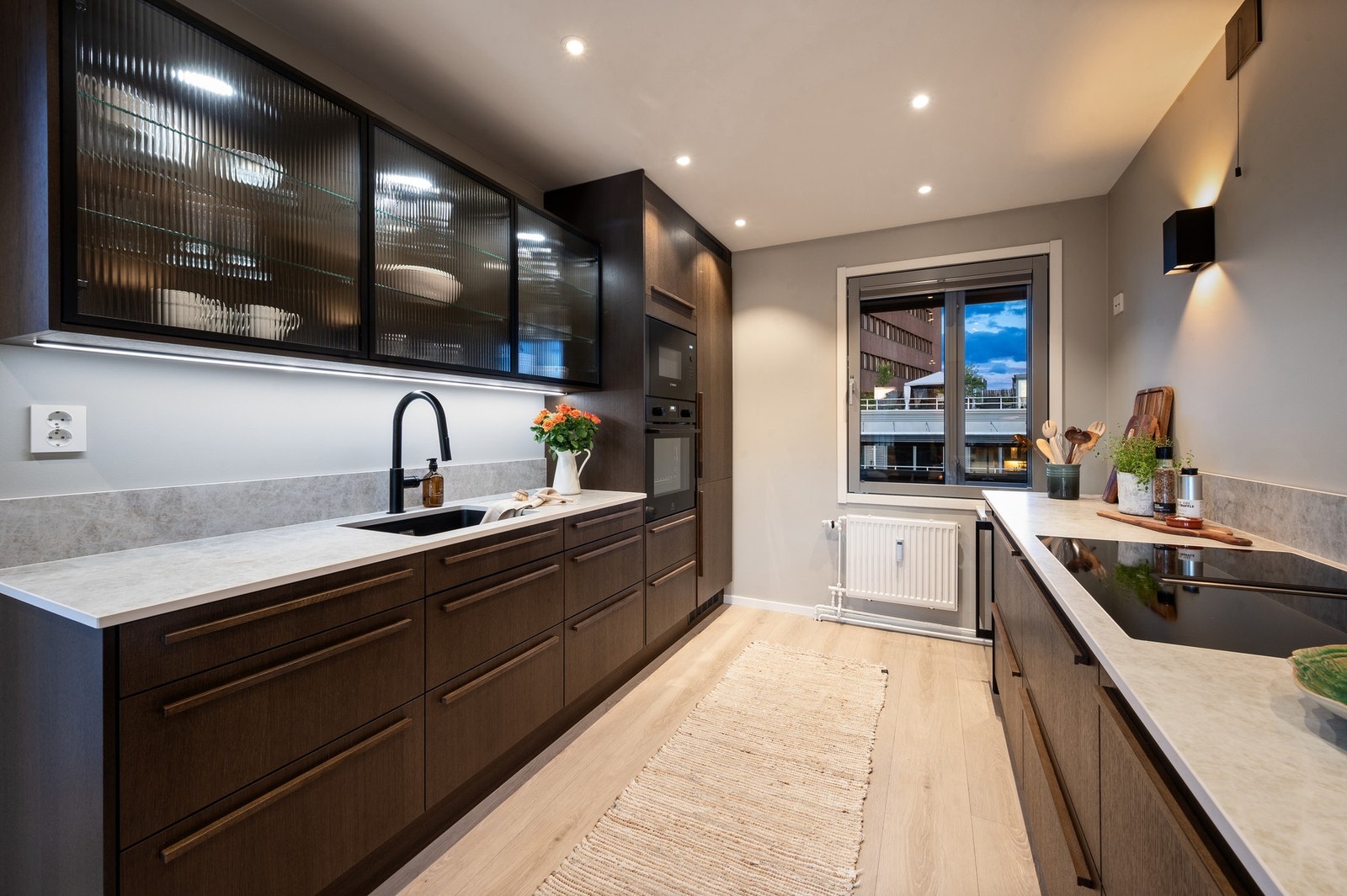 Moderne kjøkken med mørke fronter, integrerte hvitevarer og god belysning. Galleribilde