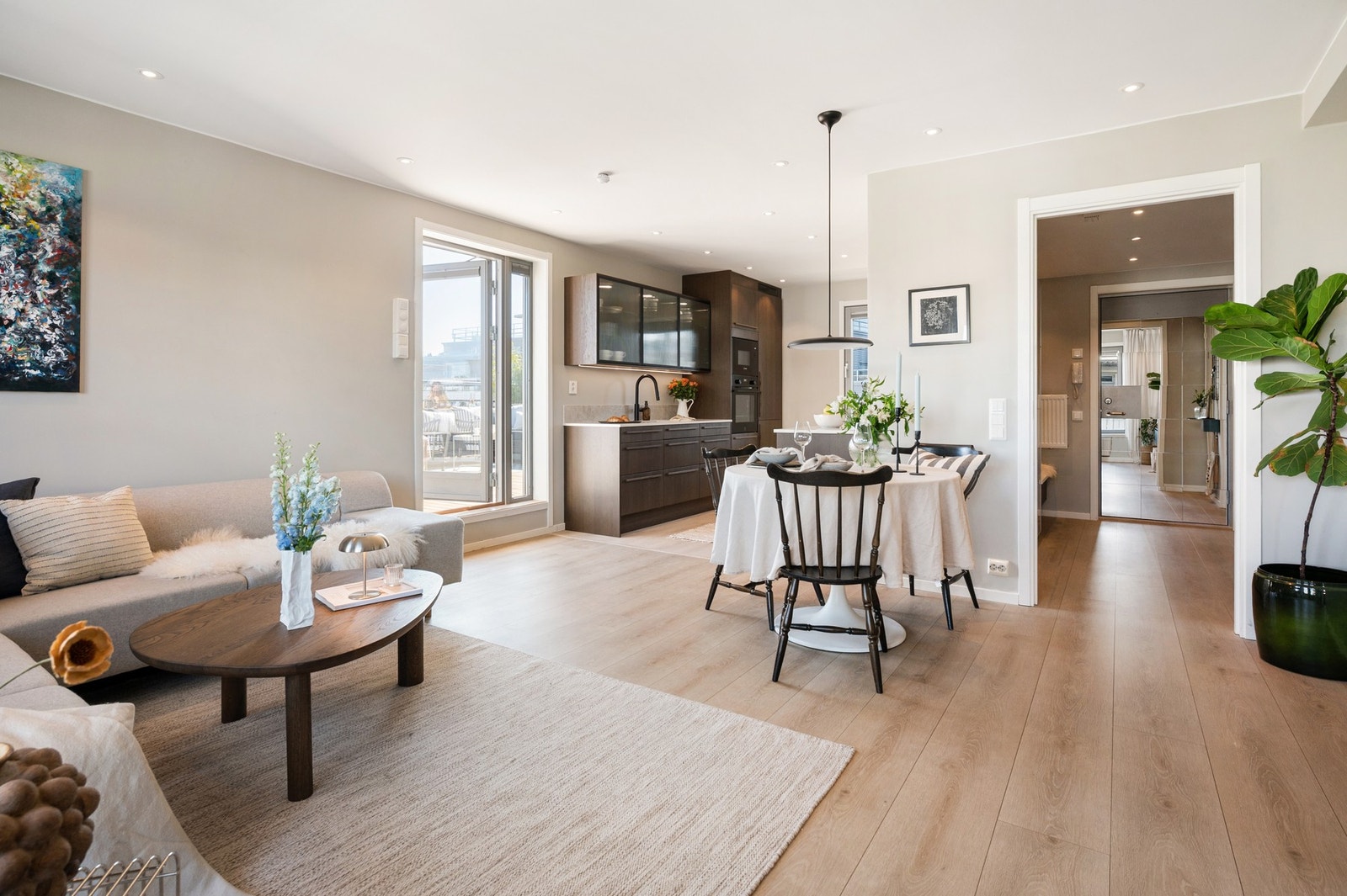 Åpen stue- og kjøkkenløsning med lys innredning, spiseplass og utgang til terrasse. Galleribilde