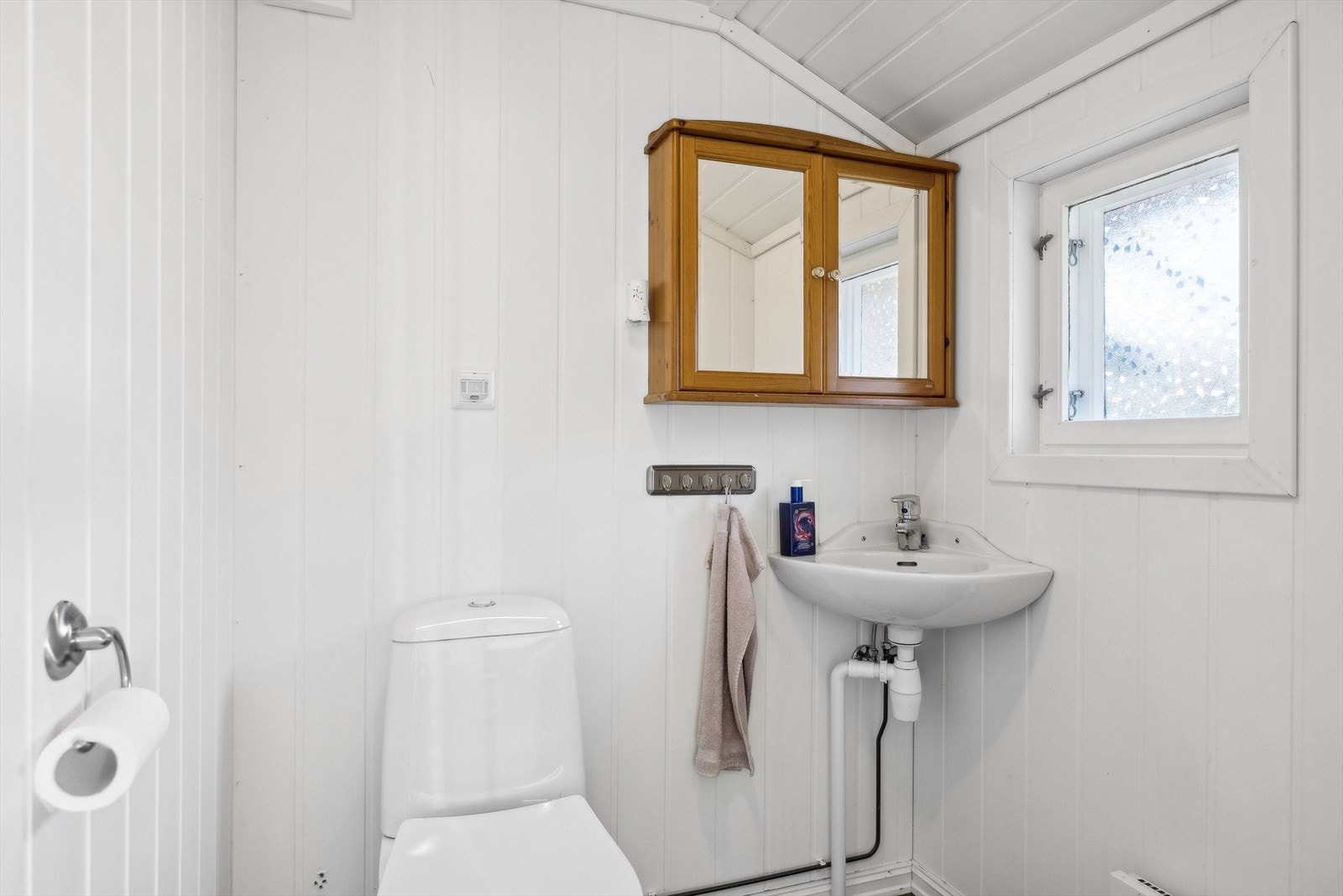 oalettrom har Gulv tildekket med laminat flis gulv, vegger og takhimling av nyere MDF plater/panel. Det er gulv montert toalett, vegg hengt hjørnevask. Galleribilde