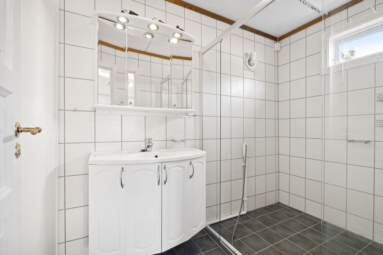 Baderommet har vegger tildekket med fliser, montert skyvedørs skap front med panelte vegger innvendig i skap og takhimling av slett malt himling. Galleribilde