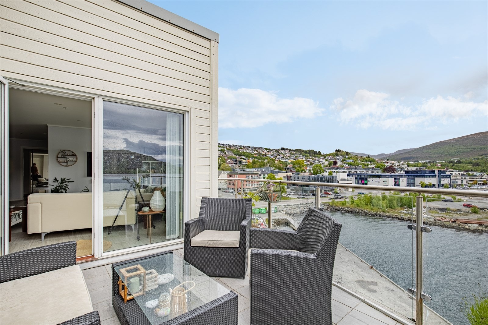 Flislagt veranda på ca. 10 m² med rekkverk av glass og stål | her er det flott utsikt mot sentrum, sjøen og fjella og øyene omkring Galleribilde