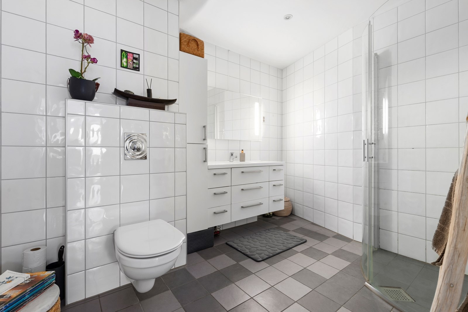 Helfliset hovedbad med vannbåren varme i gulv | badet er utstyrt med vegghengt wc, baderomsinnredning og dusjhjørne med buede glassdører Galleribilde