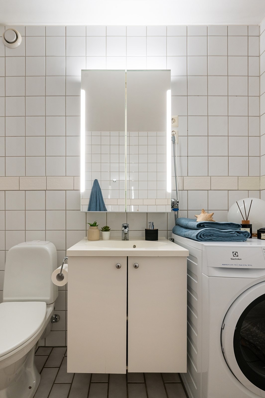 Innredningen består av vegghengt servantskap med servant. Opplegg for vaskemaskin. Galleribilde