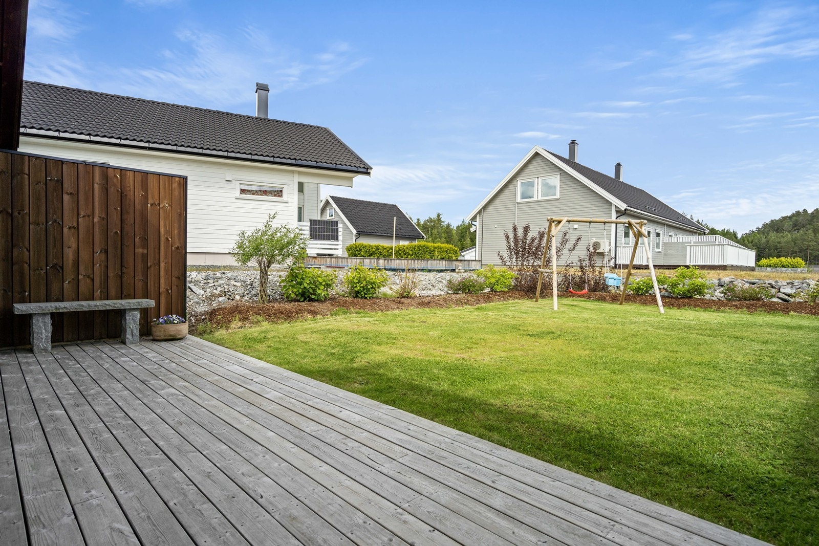 Tomten er pent opparbeidet med plen, terrasser og beplantninger Galleribilde