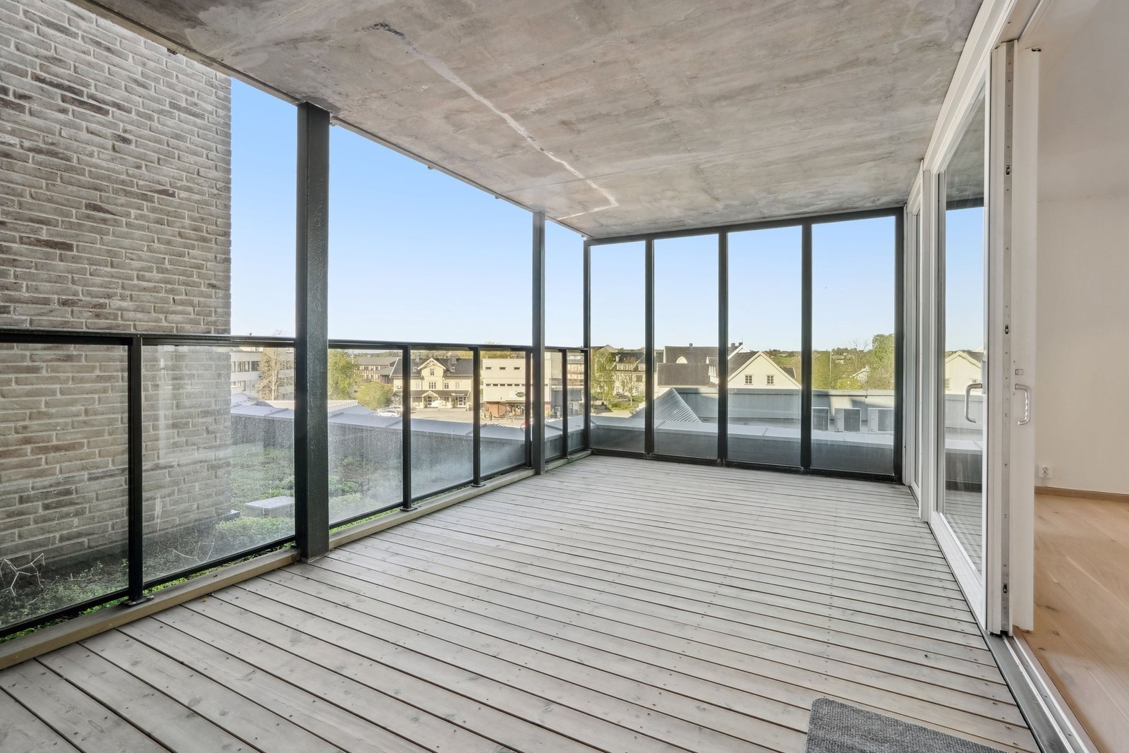 Her finner du ett stilrent glassrekkverk, hel glassvegg langs endeveggen og terassebord på fast dekke. Galleribilde