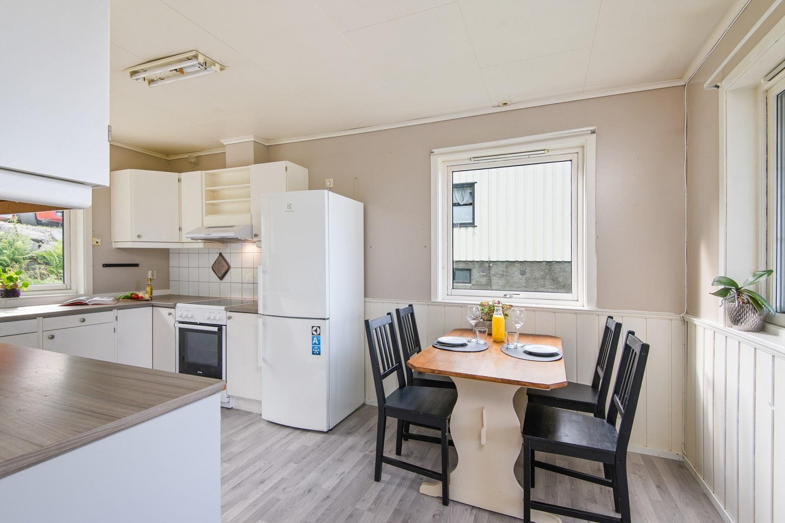 Kjøkkenet er lyse farger og har store vindusflater Galleribilde