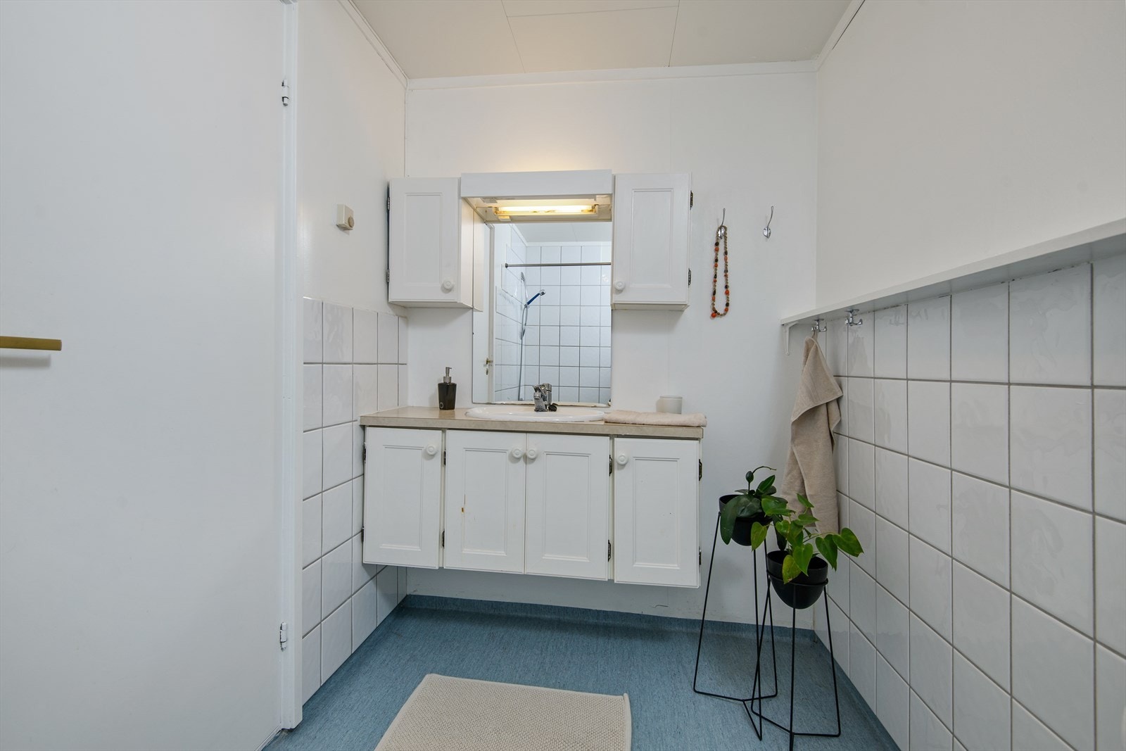 Baderommet i underetasjen har vinylbelegg med varme på gulv, fliser og malte plater på vegg, og himlingsplater Galleribilde