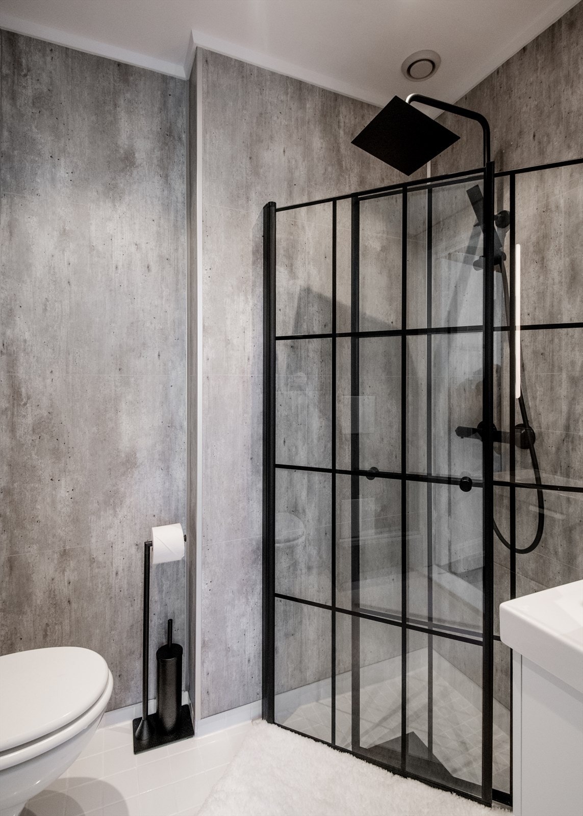 Badet er utstyrt med vegghengt wc, dusjløsning med innfellbare glassdører, servant med skap og naturlig avtrekk Galleribilde