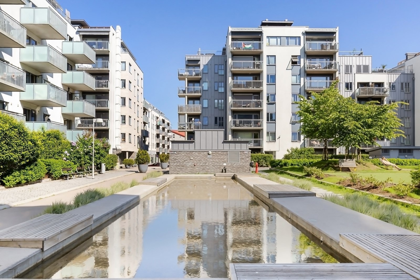 Pent opparbeidet fellesareal med asfalterte internveier, lekeplass, plen og beplantning Galleribilde