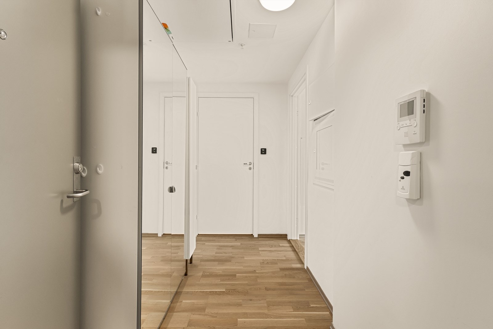 Praktisk entré/gang med skyvedørsgarderobe i speil. Man kan også merke seg at det er parkett i alle gulv, bortsett fra baderom som er helfliset. Galleribilde