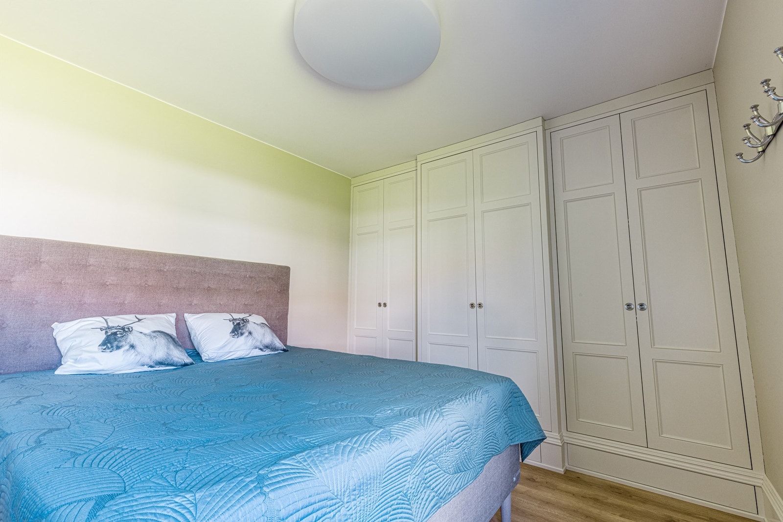 En smart, plassbygget garderobeinnredning oppbevarer klær og tilbehør ved sengens side. Galleribilde