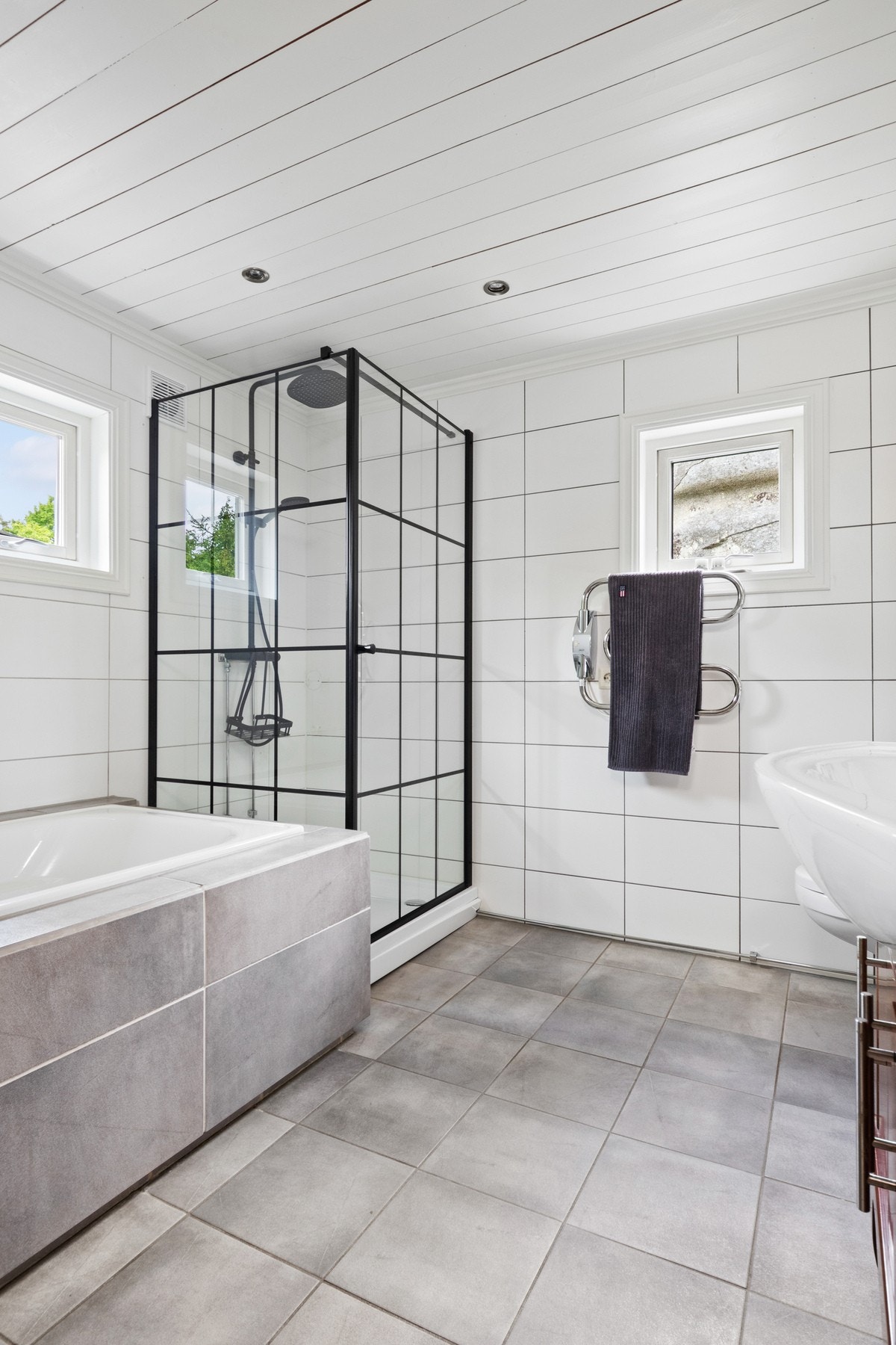 Badet har et innfliset badekar til glede for store og små, samt et nyere dusjhjørne med kabinettbunn, glassdører med sorte lister, samt regnfallsdusj og hånddusj i sort design. Galleribilde