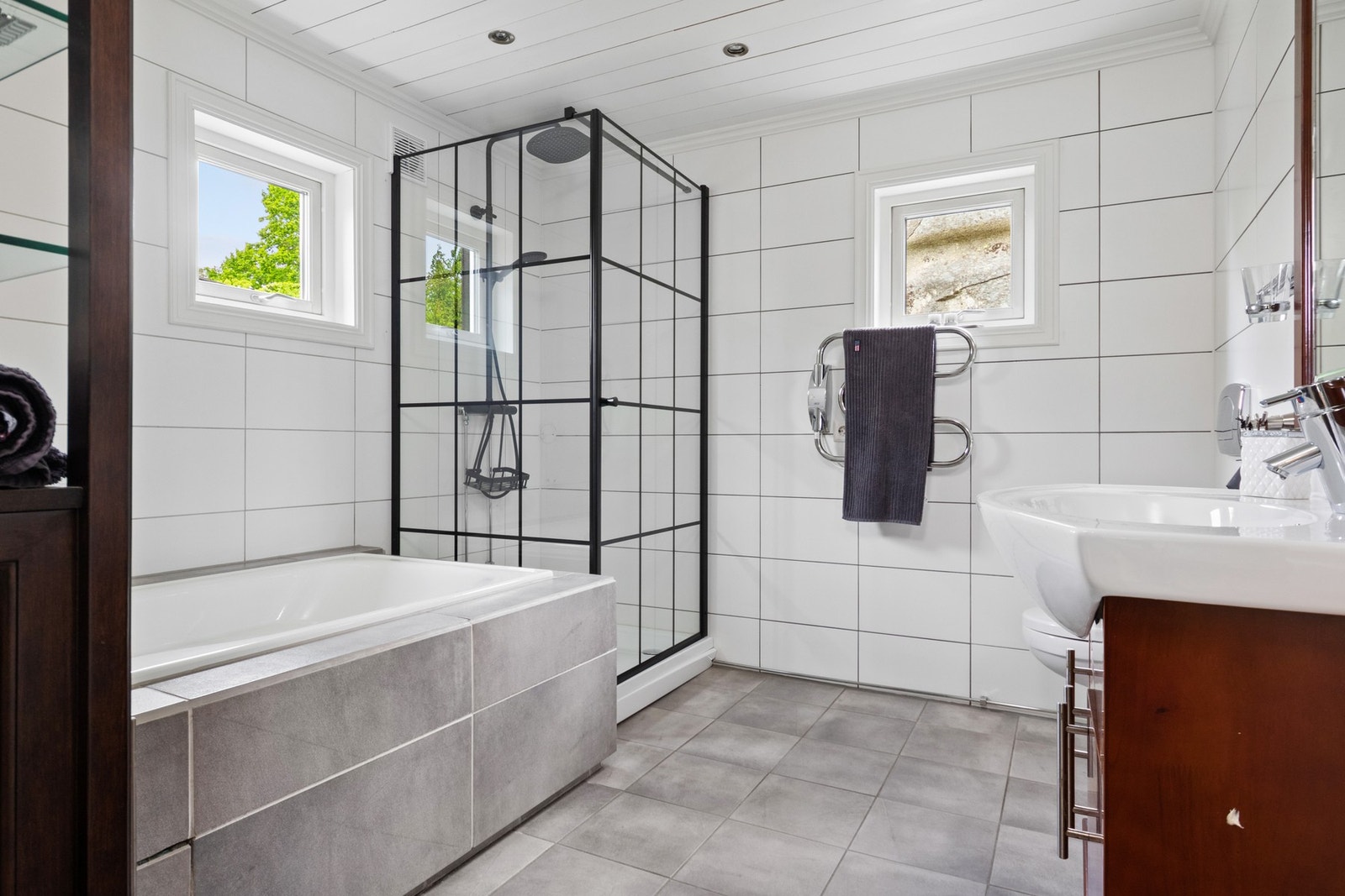 Badet i første etasje har grå fliser på gulv med vannbåren gulvvarme, hvite fliser på veggene og downlights i taket. Galleribilde