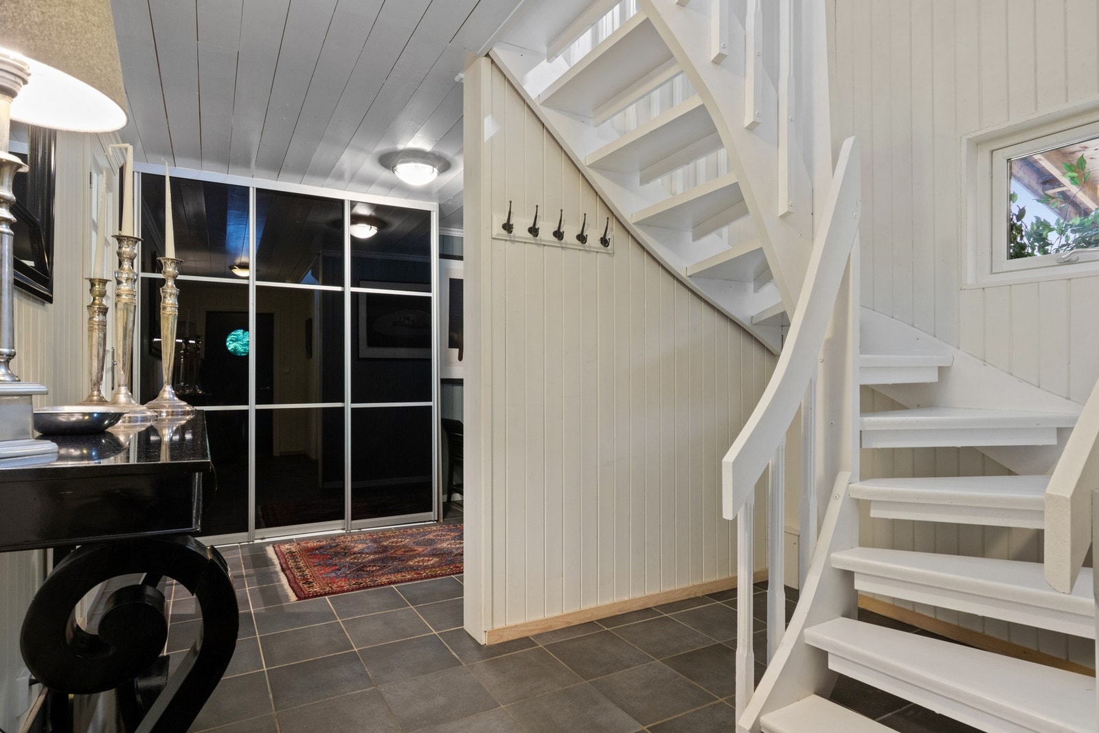 Entreen er innredet med knagger på veggen og en stor skyvedørsgarderobe. Galleribilde