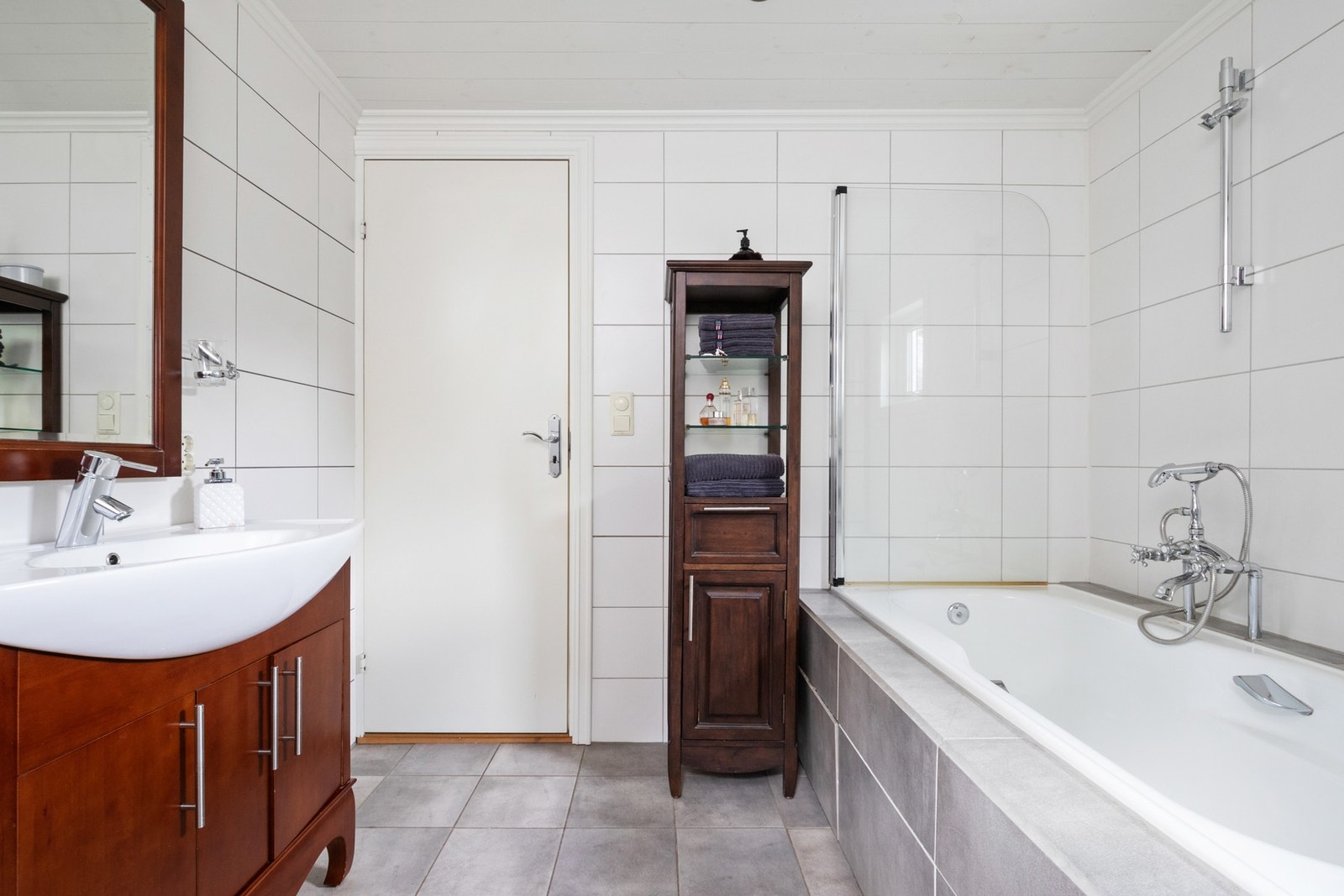 Innredningen består av servant på brunt servantmøbel, speil med overlys, et toalett og et dusjkabinett. Langs den ene veggen er det en benk med nisje for vaskemaskin og tørketrommel. Galleribilde