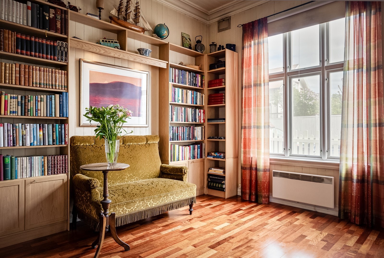 Biblioteket er innredet med bokhyller og hyggelig sittegruppe Galleribilde