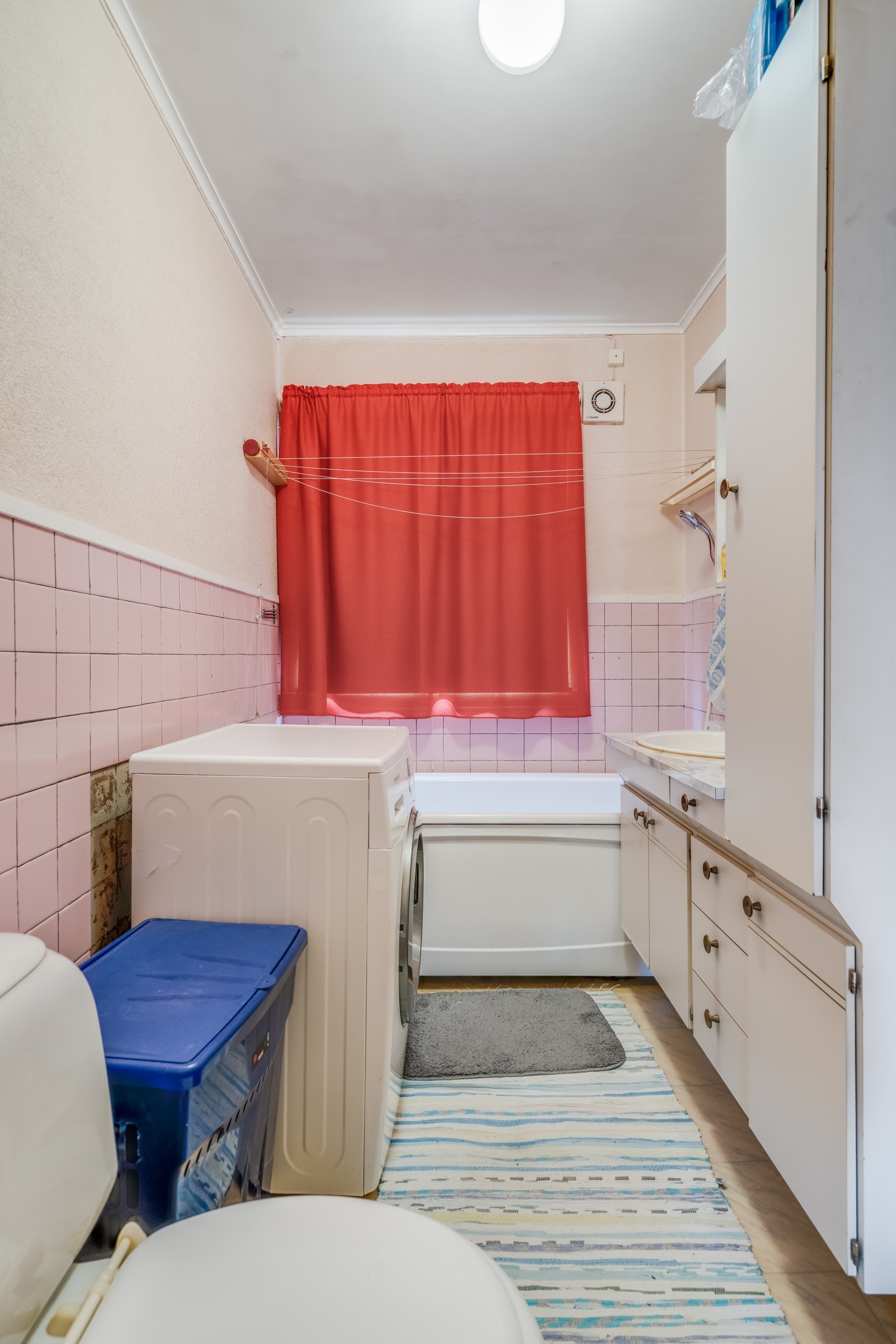 Bad i 1.etasje med belegg på gulv, flislagte vegger samt malte plater, vegghengt servantskap og badekar på gulv i hjørne. Galleribilde