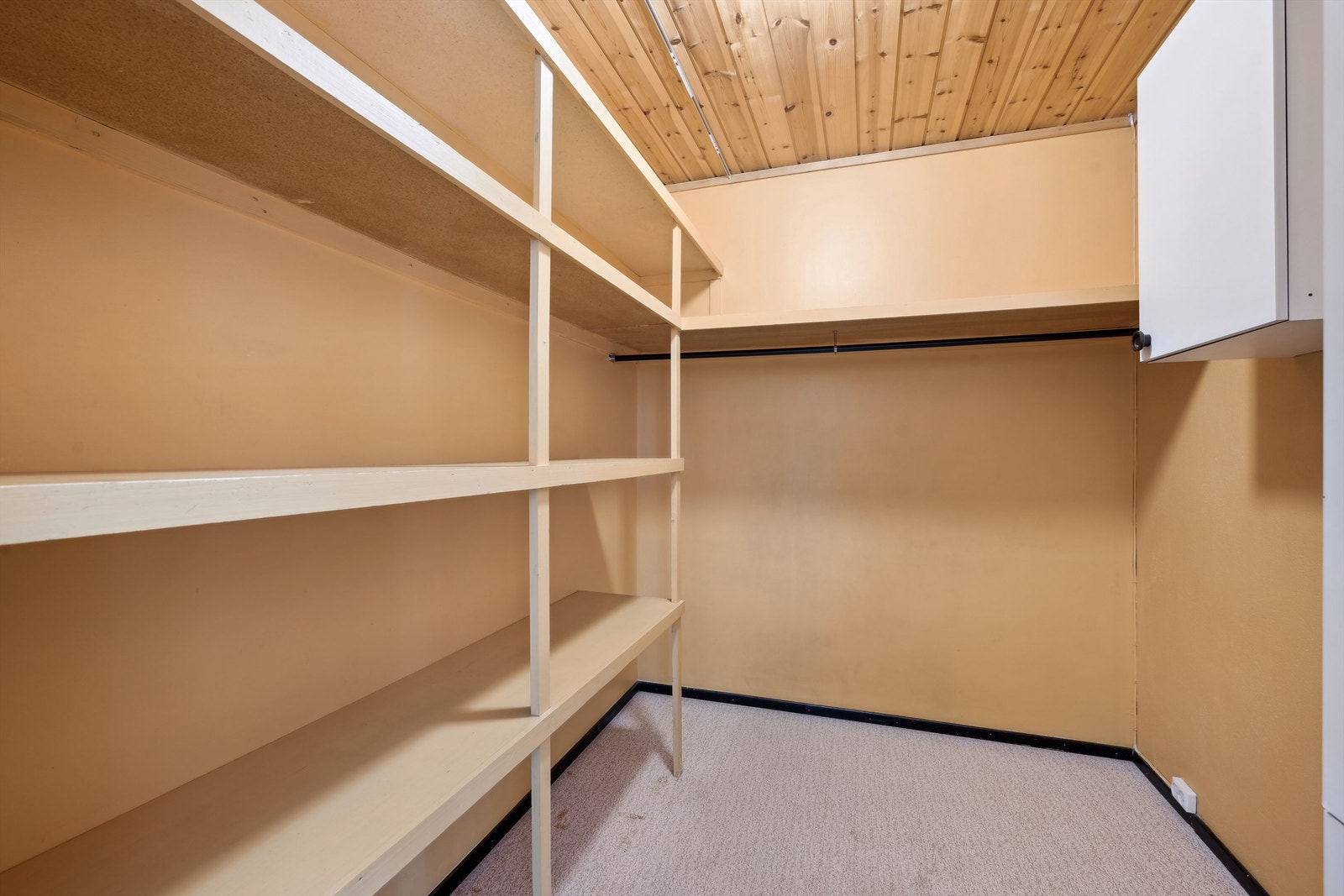 Innvendig bod med malte vegger og belegg på gulvet. Rommet er innredet med plassbygde hyller i flere høyder. Sikringsskapet er montert på veggen i boden. Galleribilde