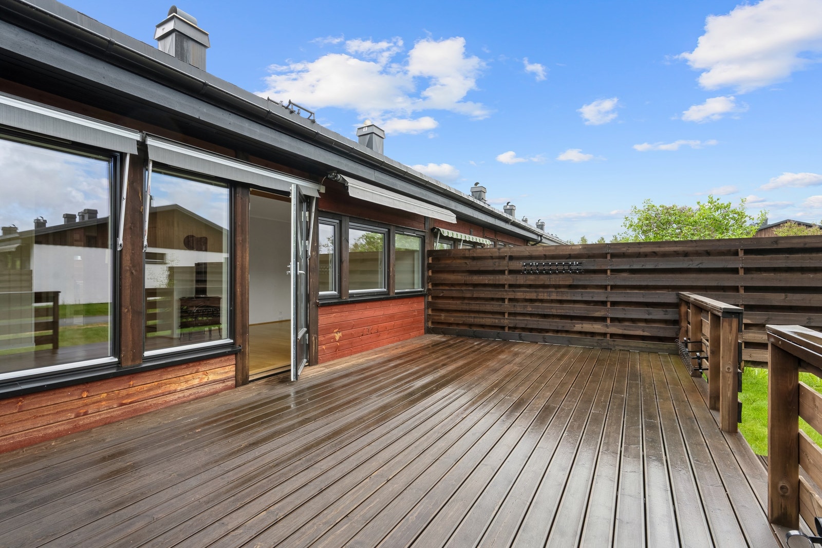 Romslig terrasse med rekkverk og tretrapp mot hagen. Galleribilde