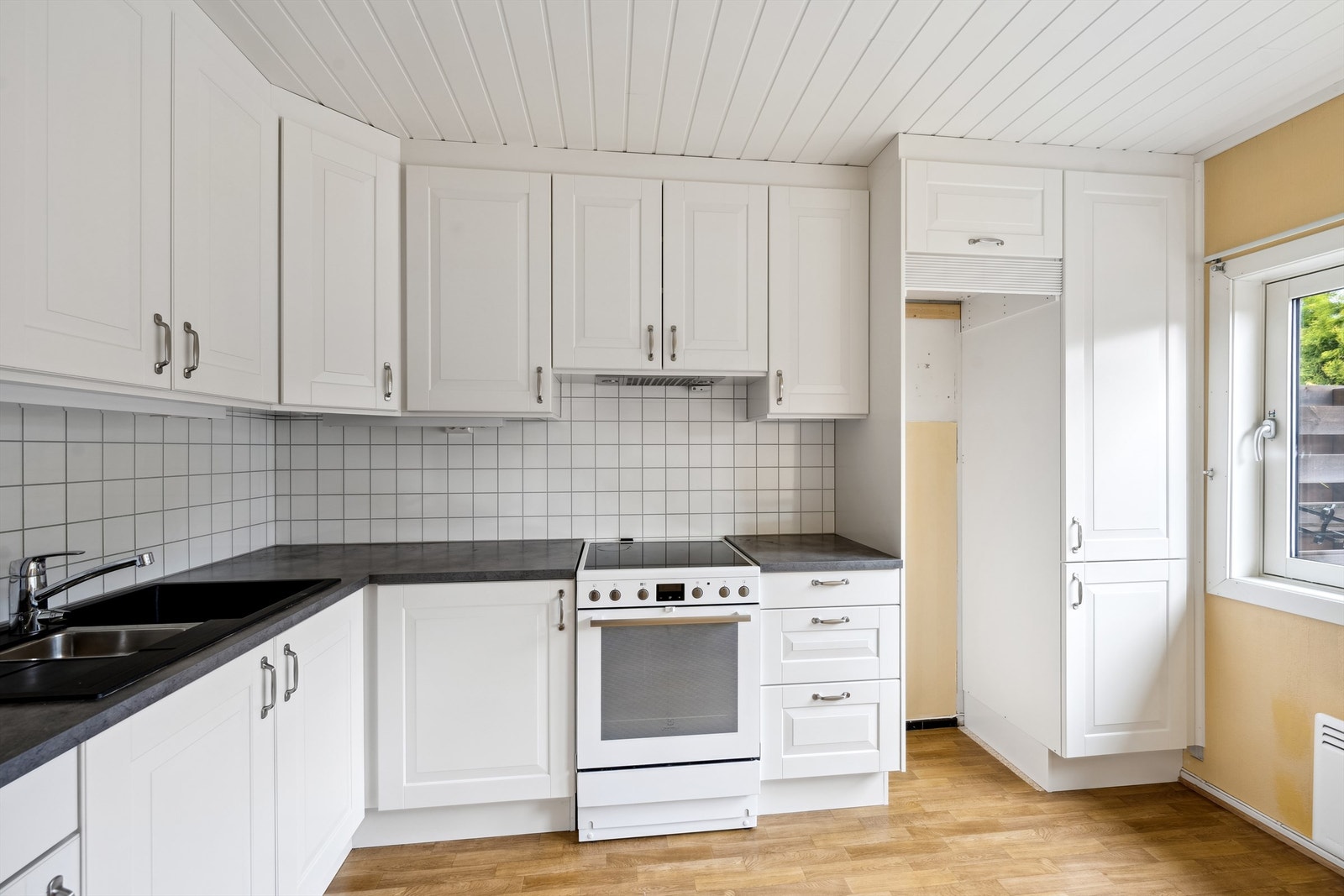 Kjøkkeninnredningen fra 2019 består av overskap, underskap og skuffer med profilerte fronter og laminerte benkeplater med nedfelt oppvaskkum i kompositt. Galleribilde