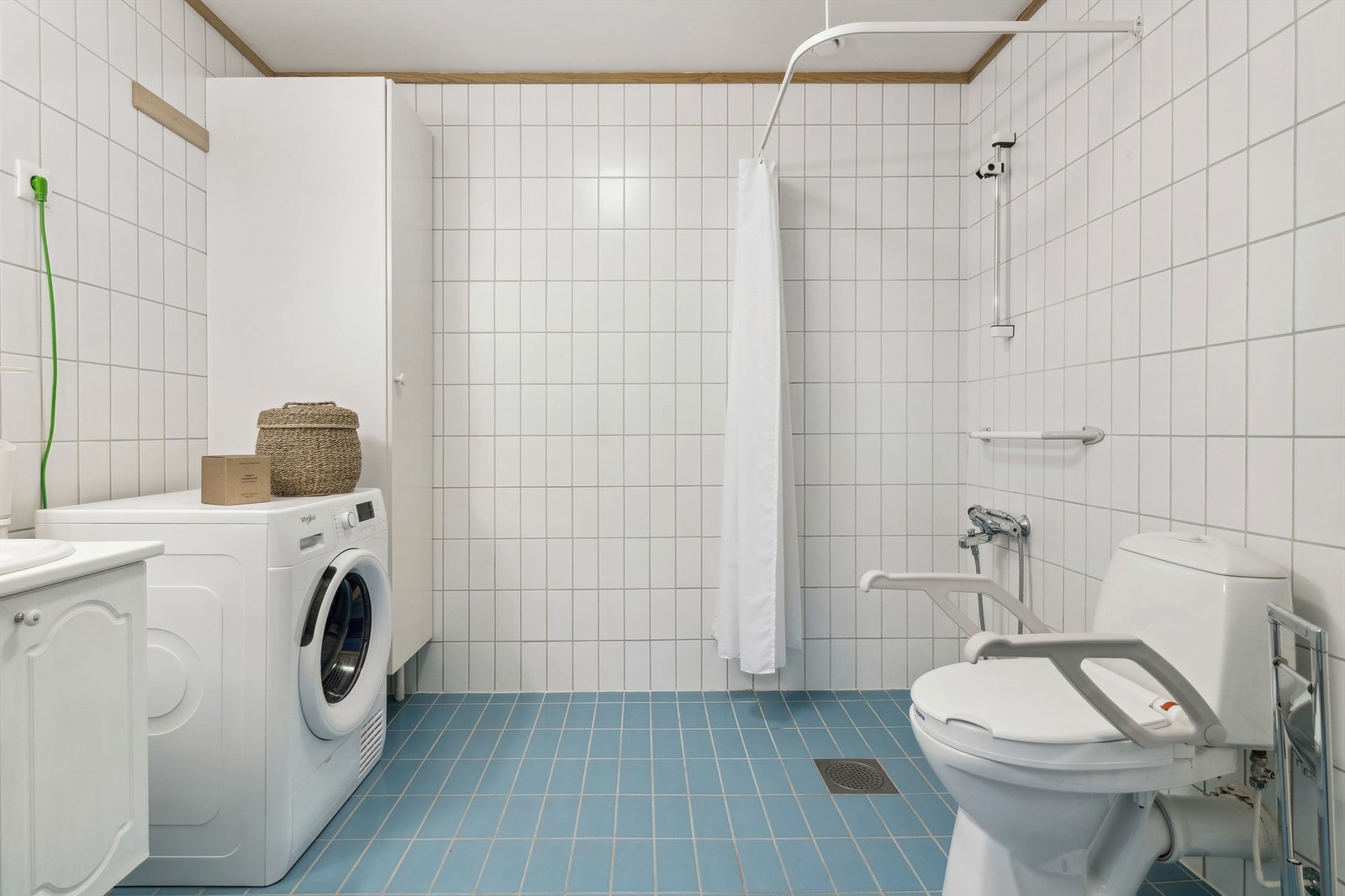 Badet er innredet med servant i baderomsinnredning, HC-toalett, dusj med forheng og praktisk opplegg for vaskemaskin. Galleribilde