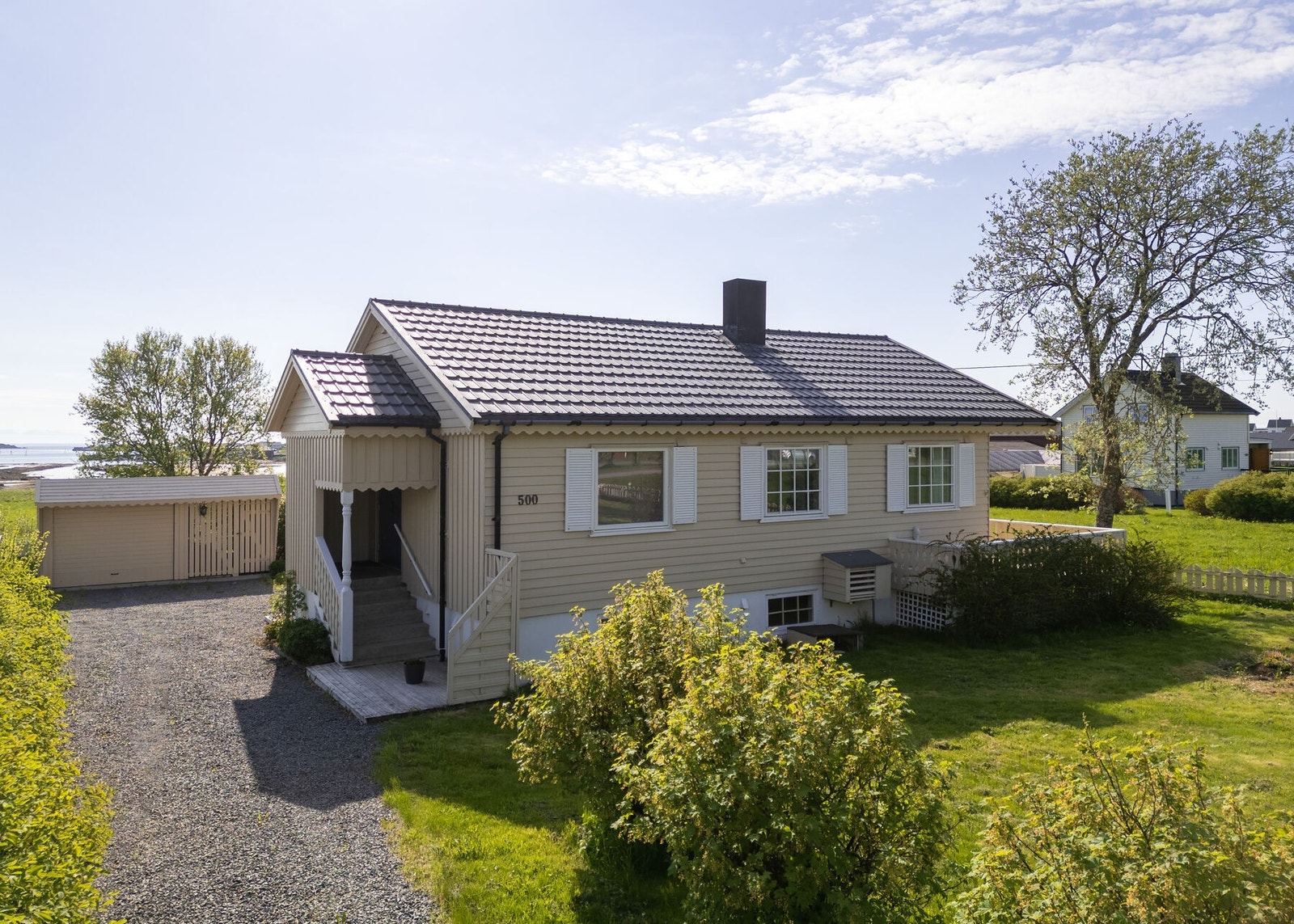 Tomten er pent opparbeidet med plen, trær og beplantning. Galleribilde